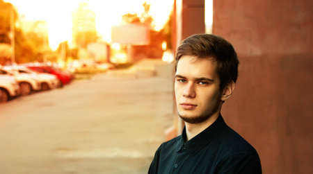 Portrait of serious young man standing outdoors in the sunsetの写真素材