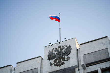 National emblem Russian Federation and flag of the Russian Federation on roof of buildingの写真素材