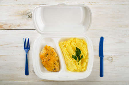 Business lunch: chiken and potato puree in styrofoam package on a wooden tableの写真素材