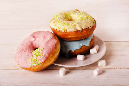 Donuts on a plate with marshmallow on a white wooden background 