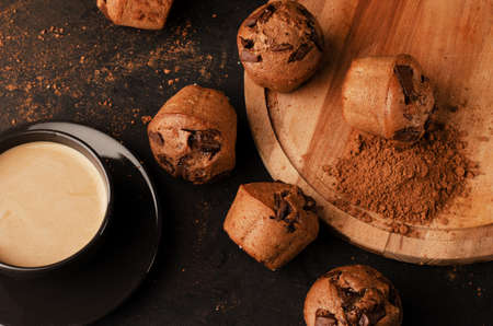 Tray with tasty muffins and cup of coffee on black table