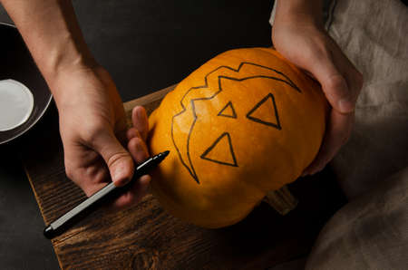 Painting Jack-o'-lantern on a pumpkin. Smiling halloween pumpkin holiday decoration. On a dark background.の写真素材