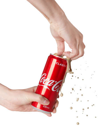 MOSCOW, RUSSIA - April 13, 2020: Opening Coca-Cola can with splash in hands isolated on a white...