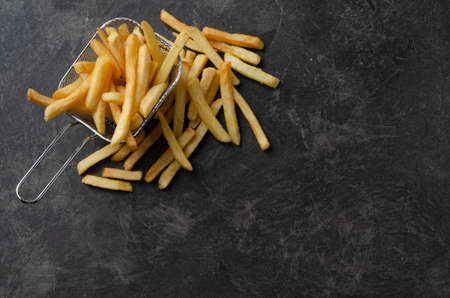French fries in metal wire basket over white kitchen table. Top view. Space for text.の写真素材