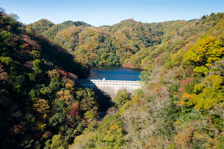 dam on a reservoir in the mountains in the autumn forestの写真素材