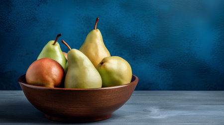 Ripe pears in a wooden bowl on a blue background.の素材