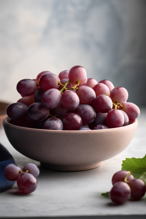 Bunch of red grapes in a bowl on a gray background.の素材