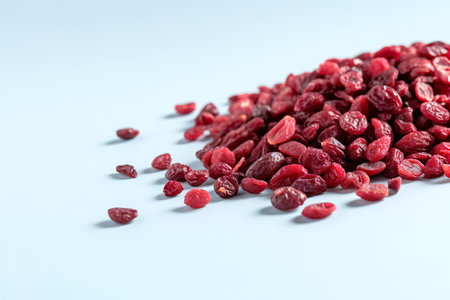 Heap of dried cranberries on blue background. Copy space.の素材