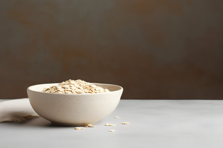 Raw oatmeal in a ceramic bowl on a gray background, copy spaceの素材
