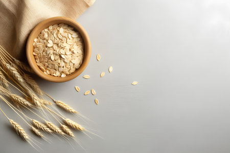 Oat flakes in bowl and ears of wheat on grey background.の素材