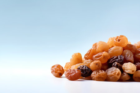 Heap of raisins on blue background with copy space.の素材