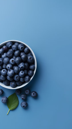 Blueberries in a bowl on blue background, top view, copy spaceの素材