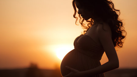 Pregnant woman on sunset background. Silhouette of a beautiful pregnant woman in a dressの素材
