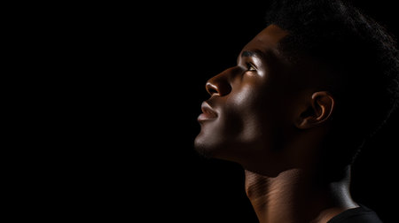 profile of young african american man looking up isolated on blackの素材