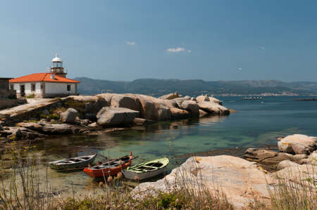 Lighthouse and three boats in a small beach in galicia, Spainの写真素材