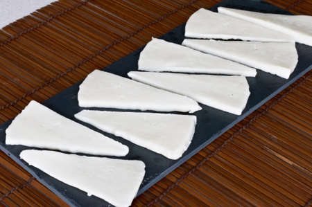 Some slices of goat cheese on a slate trayの写真素材
