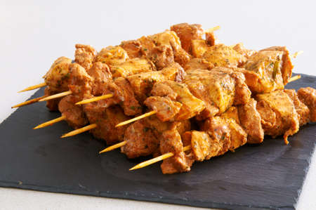 Meat brochettes on a black slate trayの写真素材