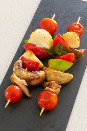 Vegetable brochettes on a black slate trayの写真素材