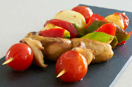 Vegetable brochettes on a black slate trayの写真素材