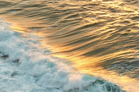 Golden reflections of the sun on a wave at sunsetの写真素材
