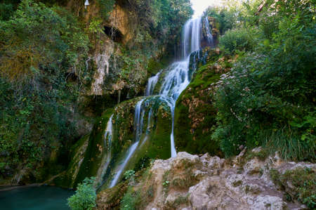 Waterfall falling from the centre of the town of Orbaneja del Castillo, Burgos, Spainの写真素材
