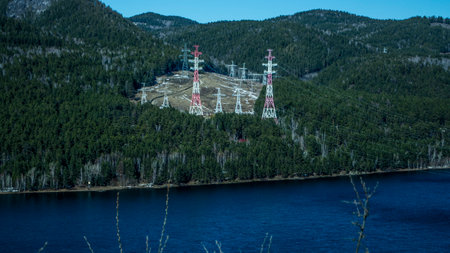 High towers of overhead power lines among the forest on the bank near the Yenisei River. Krasnoyarsk...
