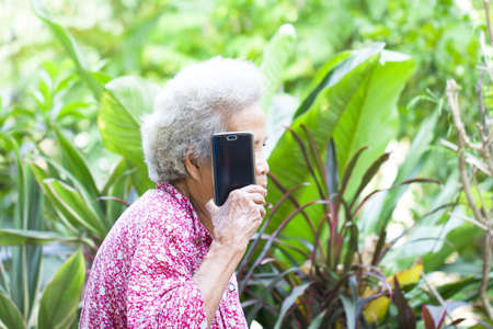 Happy asian senior woman using the mobile phone at home
