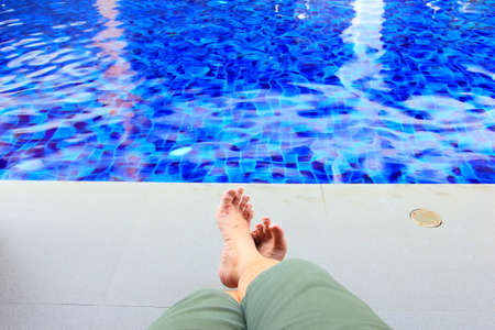 Man feet by the swimming pool relaxing on vocationの写真素材