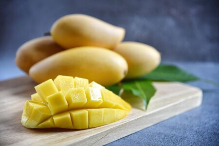 Mango slice with Fresh ripe mango and green leaves on a wooden in black  background. Tropical fruits. Selective focus. Free space for your text.の写真素材
