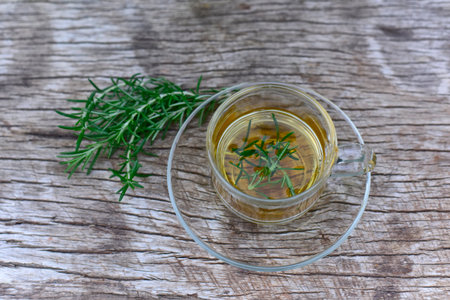 Top view Herbal rosemary tea in a glass cup on wooden vintage background. Rustic style and bunch of fresh rosemary.  Soft selected focusの写真素材