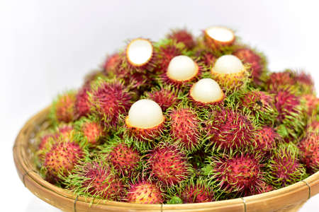 Rambutan, Thai fruits in a bamboo basket placed on white background. Fresh rambutan summer fruit from garden in Thailand. selected focusの写真素材
