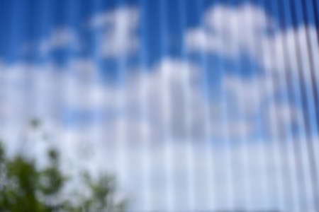 blurry view blue sky with cloud through soft white curtain from bedroom. abstract  blue sky with cloud blurry bakground. Out of focus background - nature shadow of green treesの写真素材