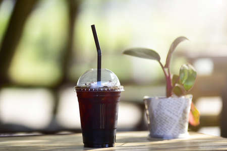 Close up of take away plastic cup of iced black coffee (Americano) on wooden table.の写真素材