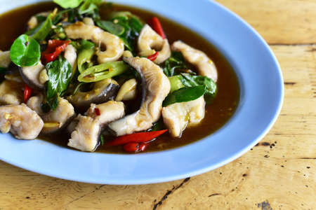 Close up Stir-fried fish (Hemibagrus wyckioides) with herbs and spices on wooden table. Authentic Thai food.の写真素材