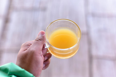 Male hands hold cup of ginger tea on wooden background. The concept of drinking herbal drinks for...