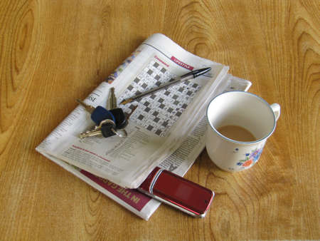 A completed crossword puzzle with a cup, a pen, some keys, and a cell phoneの写真素材