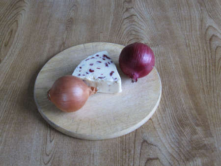 Cheese with two onions on a breadboard の写真素材