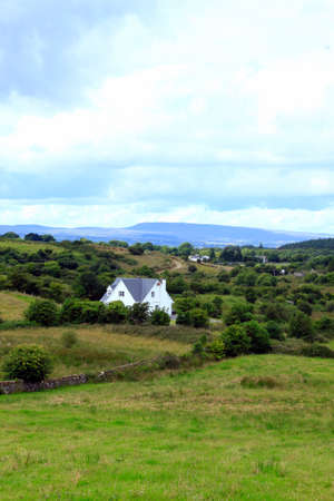 A landscape a house, some forest and distant mountainsの写真素材