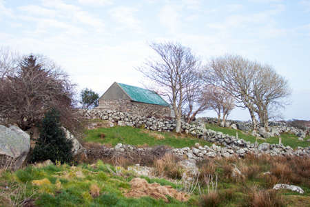 An old shed in a bleak landscape with stone wallsの写真素材