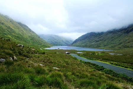 A lake on a misty day surrounded on three sides by mountainsの写真素材