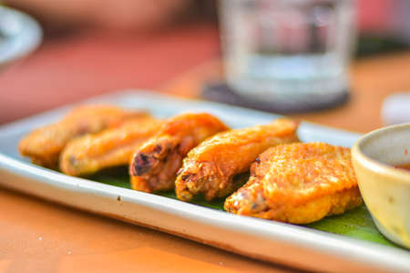 Fried chicken wings with fish sauce, served on ceramic plate. A popular appetizer dish in Thailand....