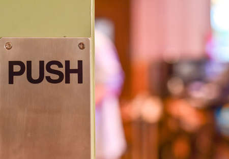 Restaurant wooden door with push sign on the metal plate. Selective focus. With copy space.の写真素材