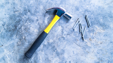Hammer and concrete nails on cement background