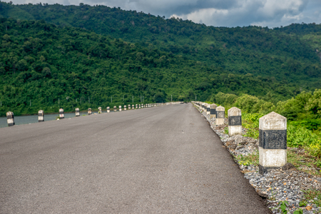 Line of stone bollards at side of asphalt roadの写真素材