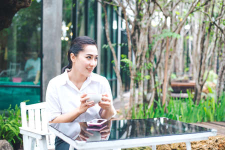 Woman drinking a coffee from a cup in coffee shop outdoors,She raised a cup of coffee and looked...