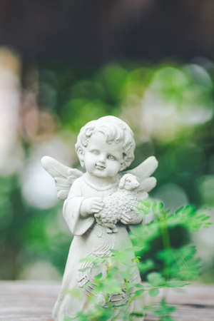 Cupid sculpture in garden,background is blurred bokeh.の写真素材