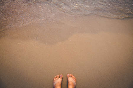 barefoot stand on sand beach with wave