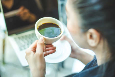 woman's hand holding a cup of hot coffee on the office desk,Soft focusの写真素材