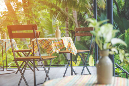 Table and wooden chairs with steel in the coffee shop, table top with colorful tablecloths and vases.at sunsetの写真素材