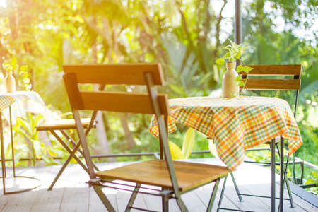 Table and wooden chairs with steel in the coffee shop, table top with colorful tablecloths and vases.at sunsetの写真素材